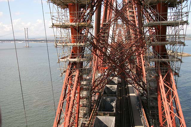 The Forth Rail Bridge  -  A train of empty coal wagons passes across the bridge beneath the scaffolding erected for painting