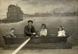 Zoom-in to the postcard size photo mounted on card as a studio portrait  -  Four in a boat  -  Portobello Pier and Edinburgh on the backdrop.