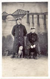 Studio Portrait of two postmen and a dog, with a backdrop of the Forth Bridge