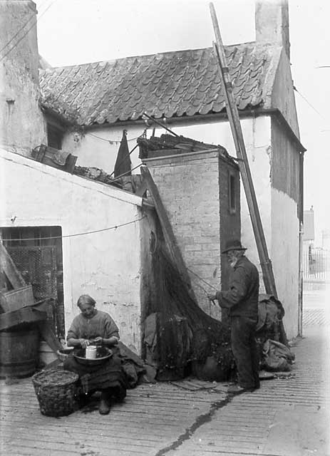 Newhaven Streets  -  Wester Close with a man mending nets and a woman shelling shell fish  -  1880s