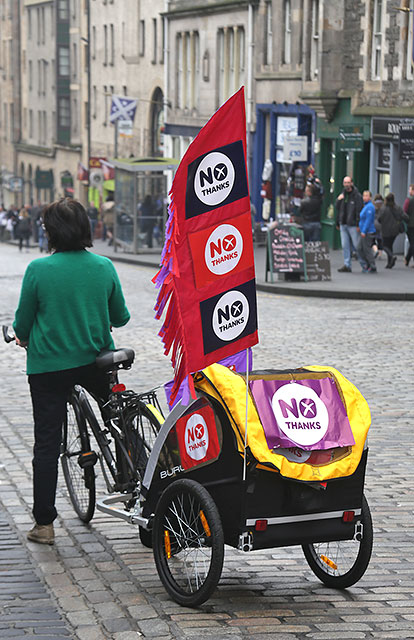 Photos taken in Edinburgh on voting day in the  Scottish Indepemdence Referendum on 18 September 2014  -  The Royal Mile  -  A cyclist with her 'No' messages pauses briefly just South Bridge as she cycles down the Royal Mile.