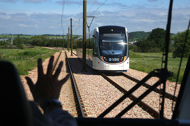 Edinburgh Tram Service  -A wave to the driver of the oncoming tram as the tram approaches Ingliston Park and Ride on its journey to Edinburh Airport Edinburgh Castle is on the horizon -  June 2014