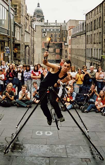 Edinburgh Festival 2003  -  Street entertainer at Hunter Square  -  A unicyclist on a tightrope juggling three flaming torches.