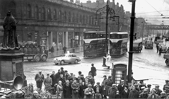 A crowd gathers at the foot of Leith Walk in May 1955.  Who is in the crowd?  Who was the speaker?  There is an interesting mix of traffic in the background.